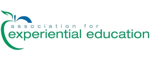 Logo for the Association for Experiential Education, featuring a stylized green and blue apple icon and the organizations name in lowercase blue and green text.