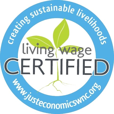 A circular blue badge with a green plant sprout in the center. Text says living wage CERTIFIED and creating sustainable livelihoods with the website www.justeconomicswnc.org around the edge.